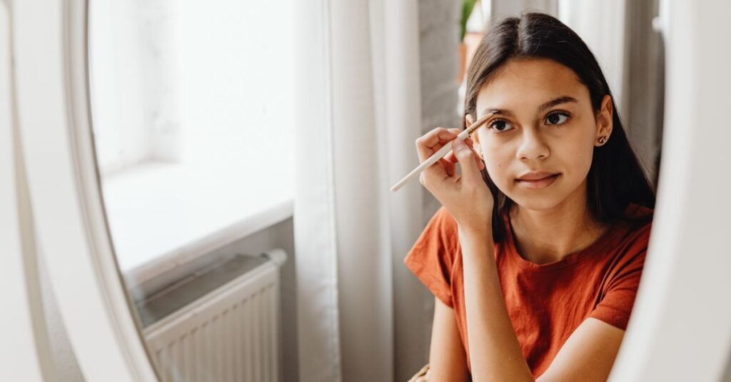 Young woman filling her eyebrows at a mirror