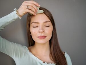 Woman using a jade gua sha tool to massage her face