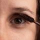Close-up of a wand applying lash product along the upper lash line
