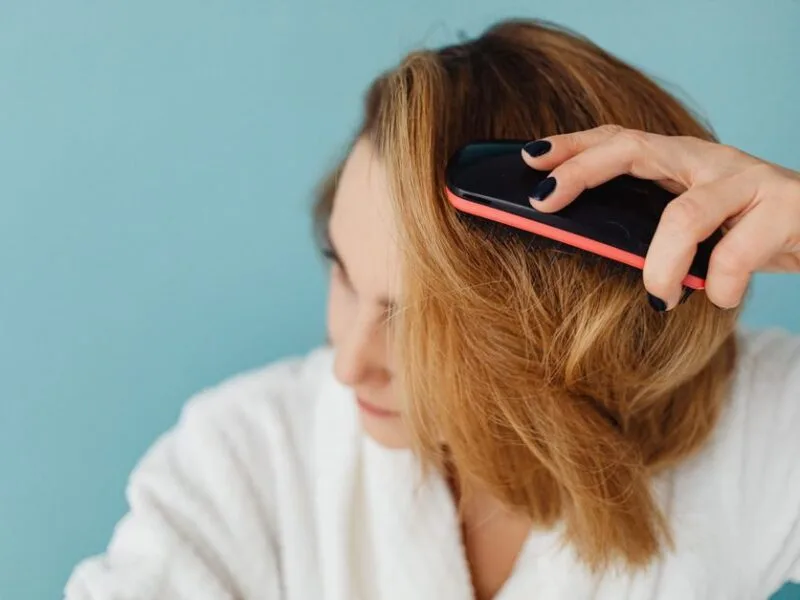 Woman brushing dry shampoo through the roots of her hair