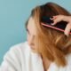 Woman brushing dry shampoo through the roots of her hair