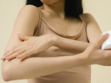 Woman applying rich body butter from a jar onto her arm for soft skin