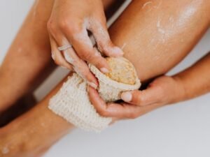 Person applying an exfoliating body scrub to smooth, glowing skin
