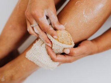 Person applying an exfoliating body scrub to smooth, glowing skin