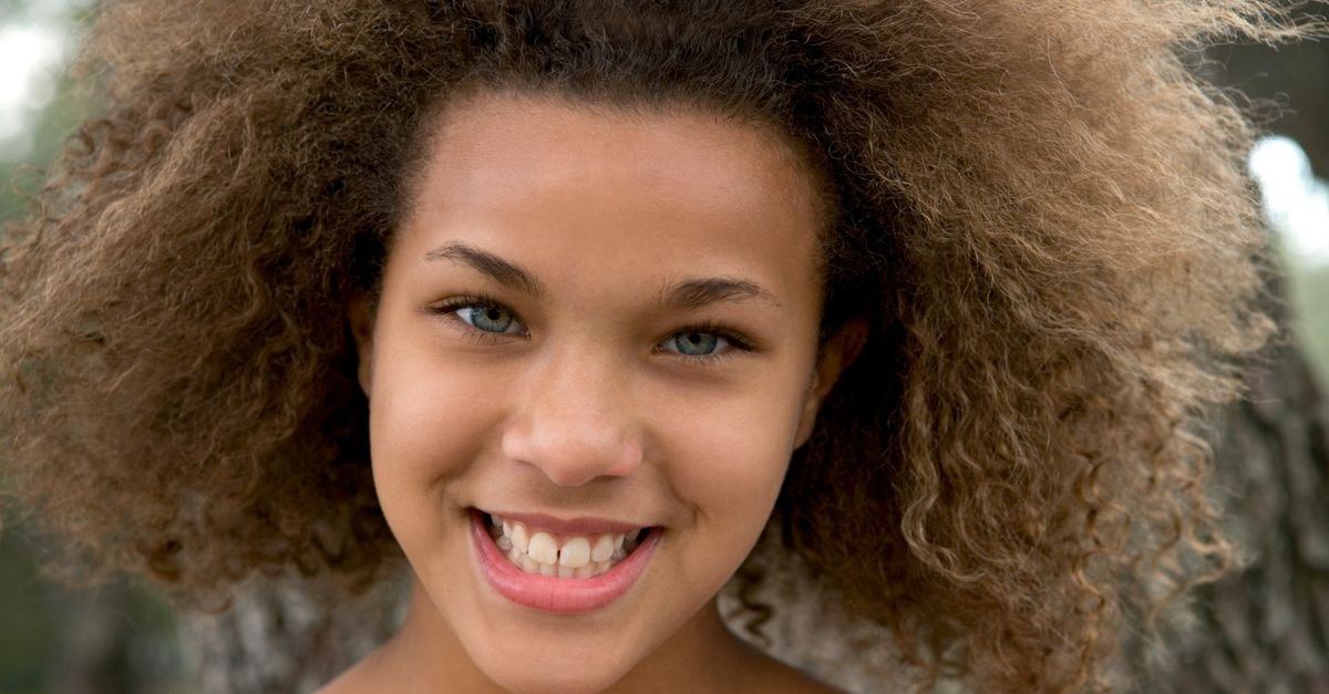 A smiling teenager with natural curly hair