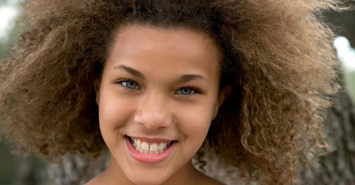 A smiling teenager with natural curly hair