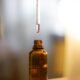 A dropper of serum over an amber glass bottle