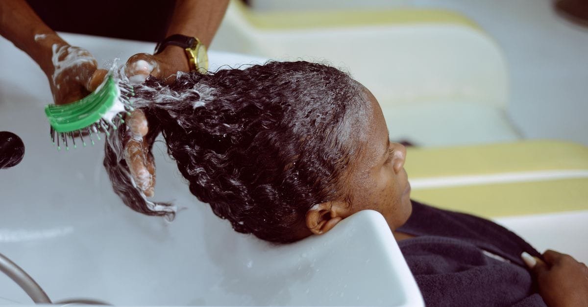 A scalp brush working shampoo through textured hair