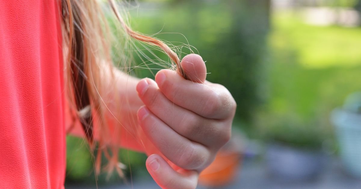 A hand holding hair ends showing splits