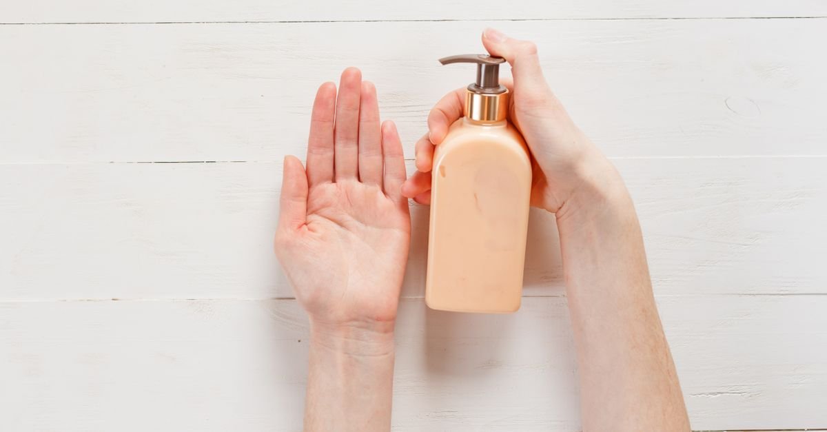 Hands holding a pump bottle of body lotion