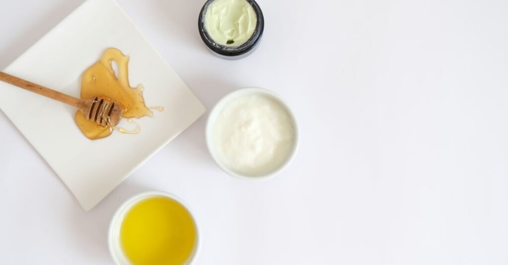Honey dipper and creams on a white flat lay