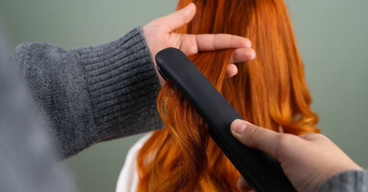 A flat iron gliding through red hair