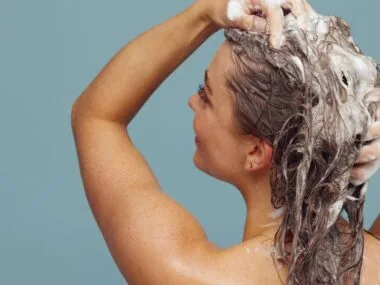 A woman lathering shampoo into her hair