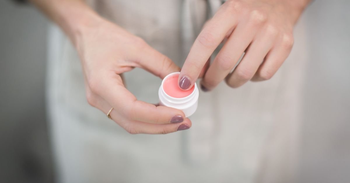 Hands holding a small jar of lip balm