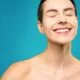 A smiling woman misting her face with a spray bottle