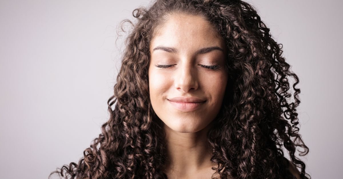 A woman with curly hair and glowing skin