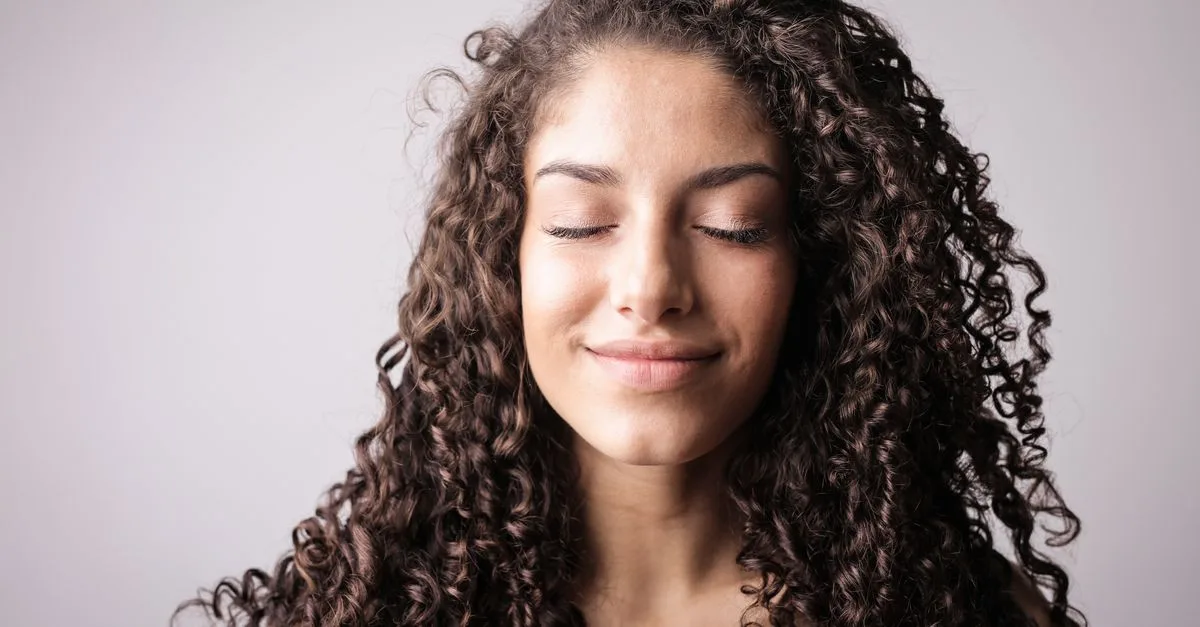 A woman with curly hair and glowing skin