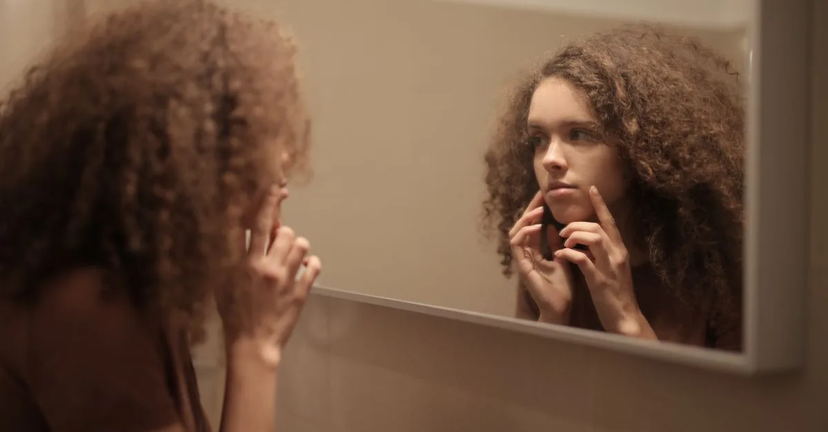 A woman inspecting her skin in the mirror