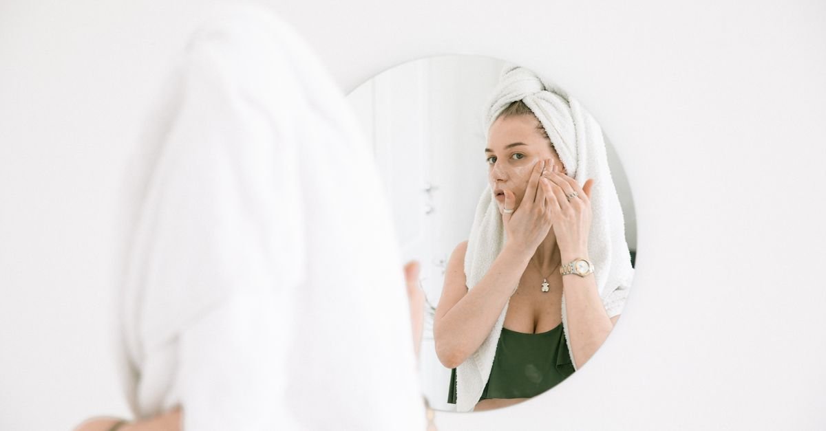 A woman checking her skin in a round mirror