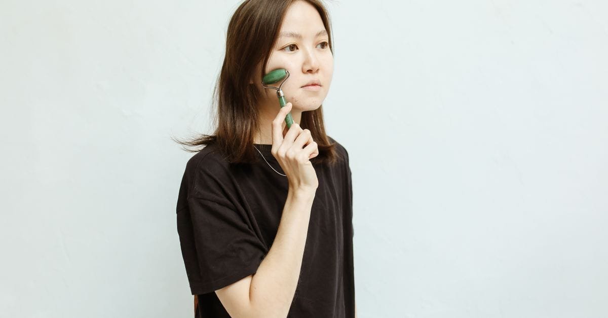 A woman using a jade roller on her face