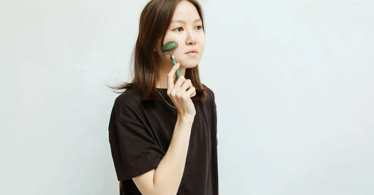 A woman using a jade roller on her face