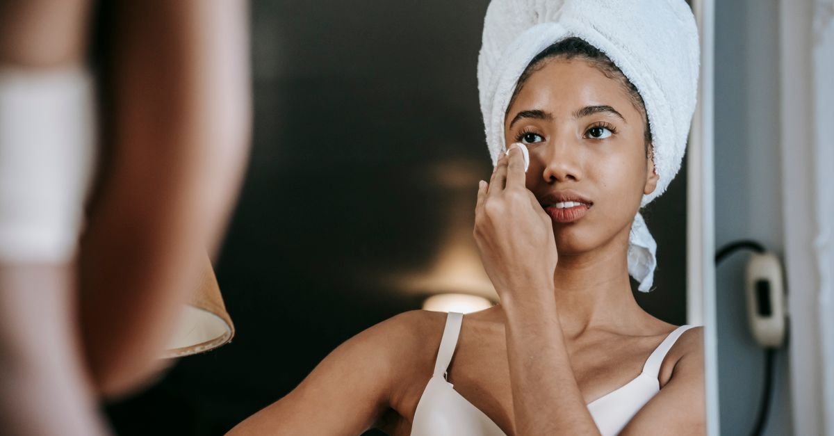 A woman applying skincare at a mirror