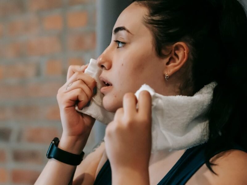 A woman dabbing her face with a towel after exercise
