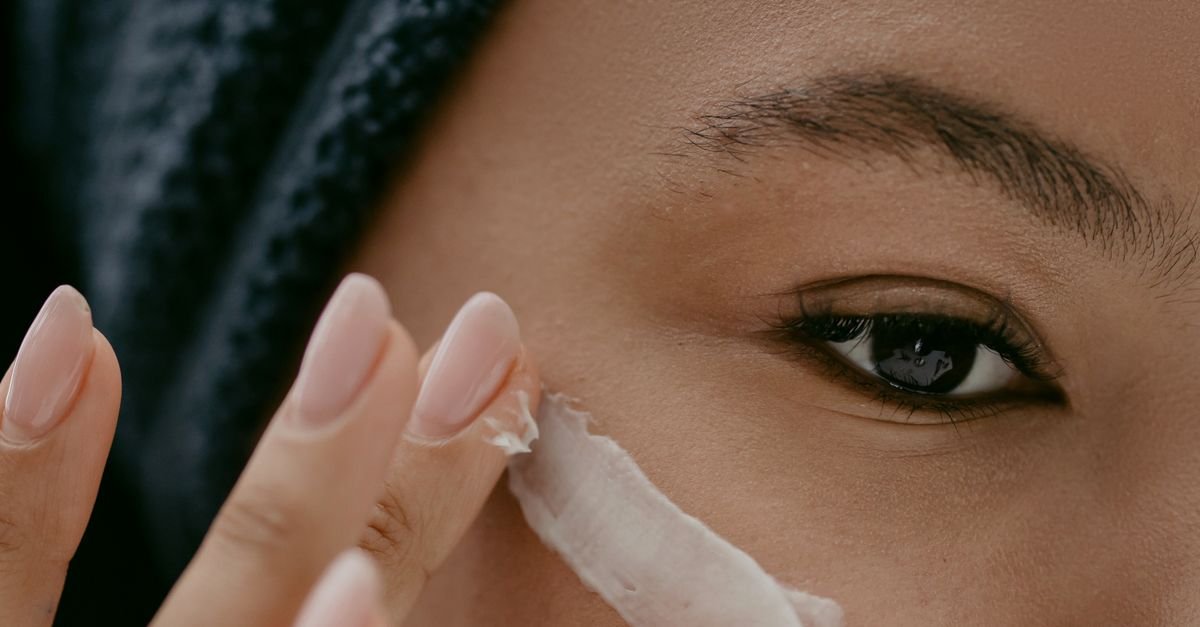 A woman applying cream near her eye