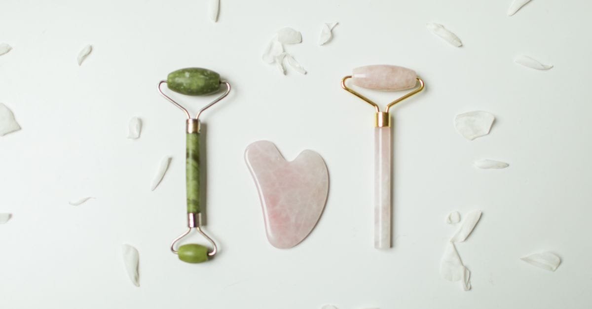 Jade and rose quartz gua sha tools in a flat lay