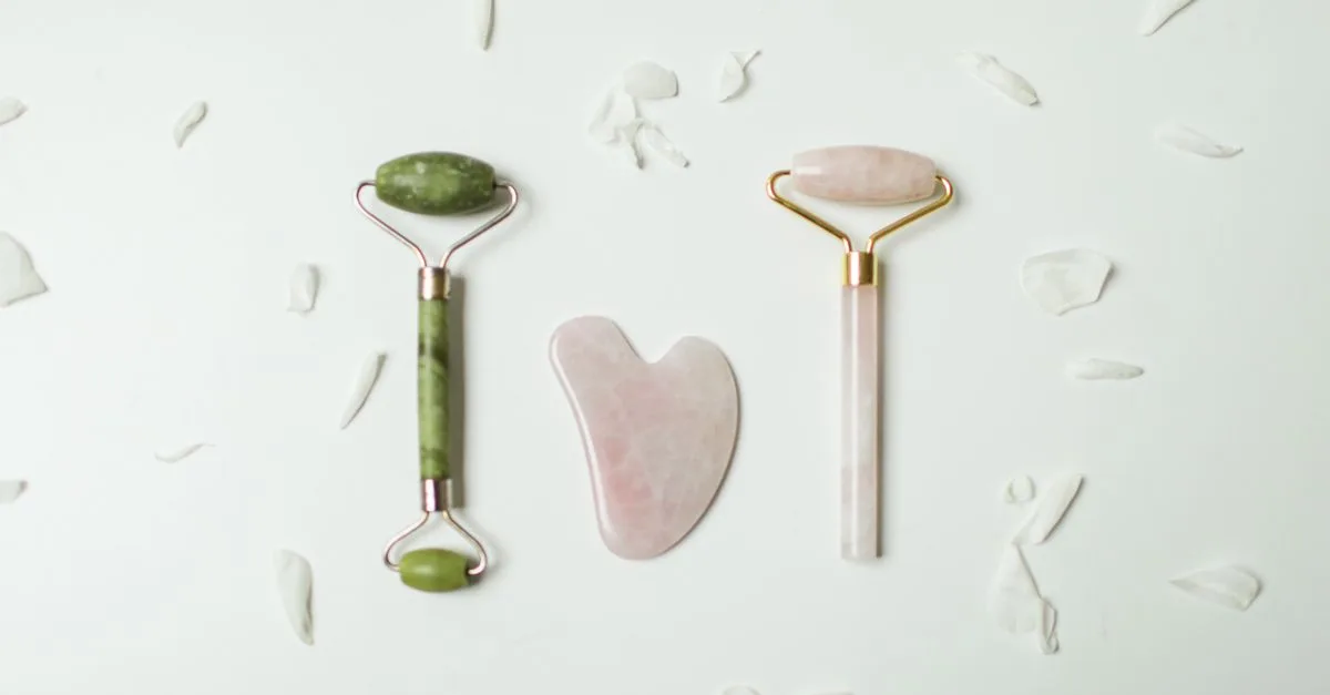 Jade and rose quartz gua sha tools in a flat lay