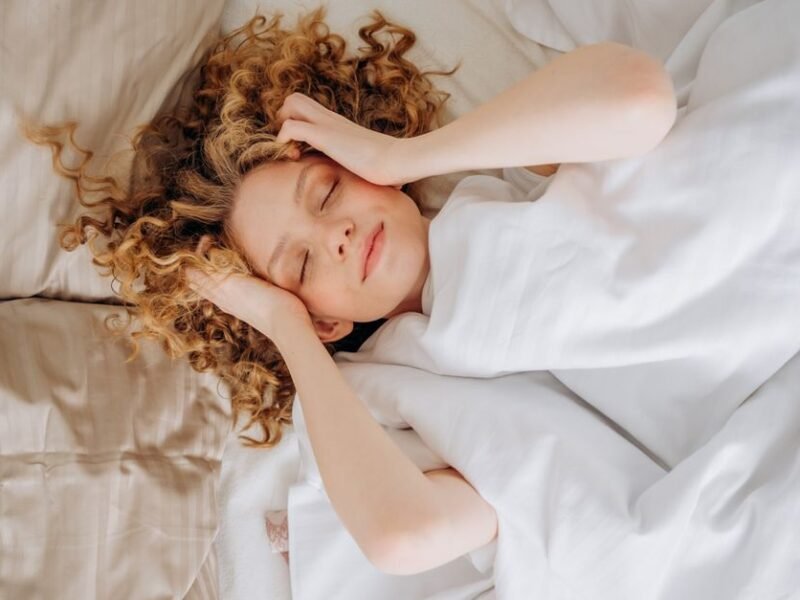 A woman lying in bed touching her forehead in the morning