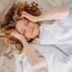 A woman lying in bed touching her forehead in the morning