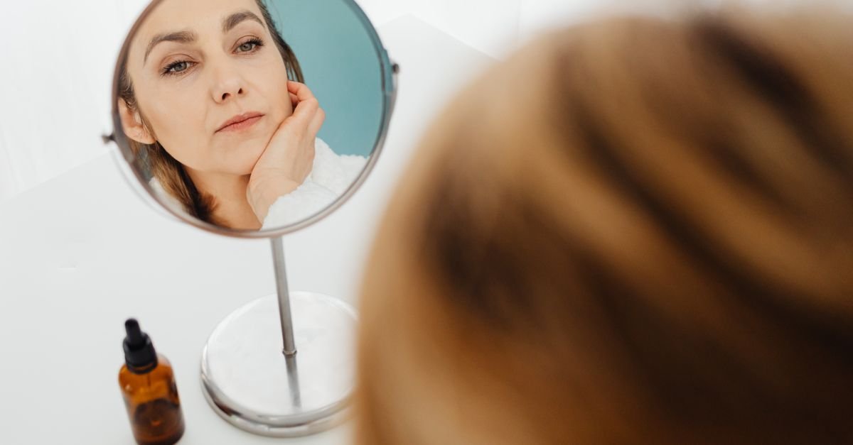 A woman examining her face in a round mirror