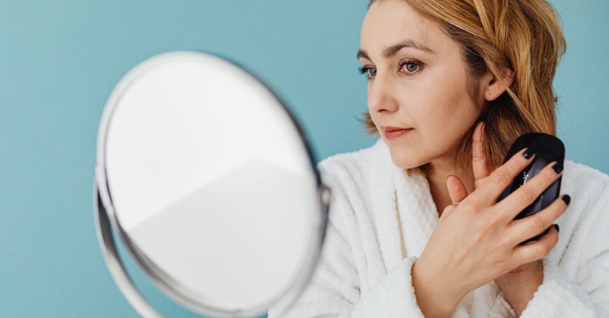 A woman checking her skin with a hand mirror