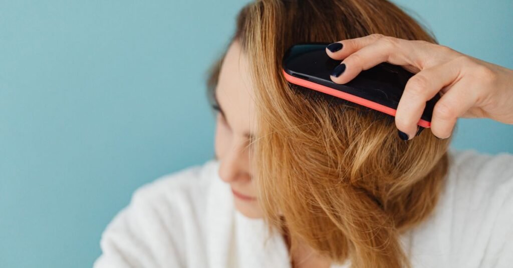 Woman in a robe brushing her hair at a teal wall