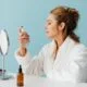A woman spritzing a facial mist at a vanity mirror