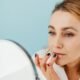 A woman applying lip balm at a mirror