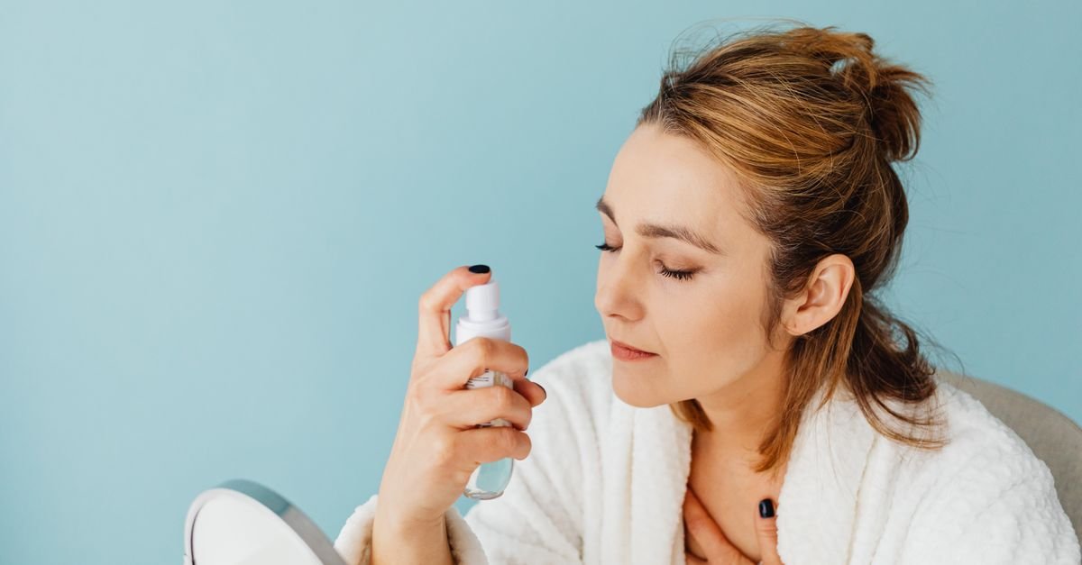 A woman applying spray product near her face