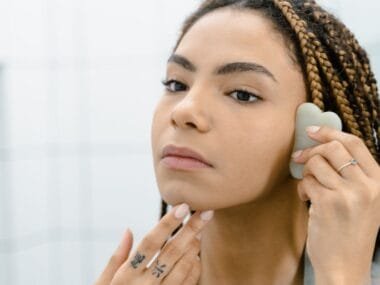 A woman using a gua sha stone on her cheek