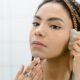 A woman using a gua sha stone on her cheek