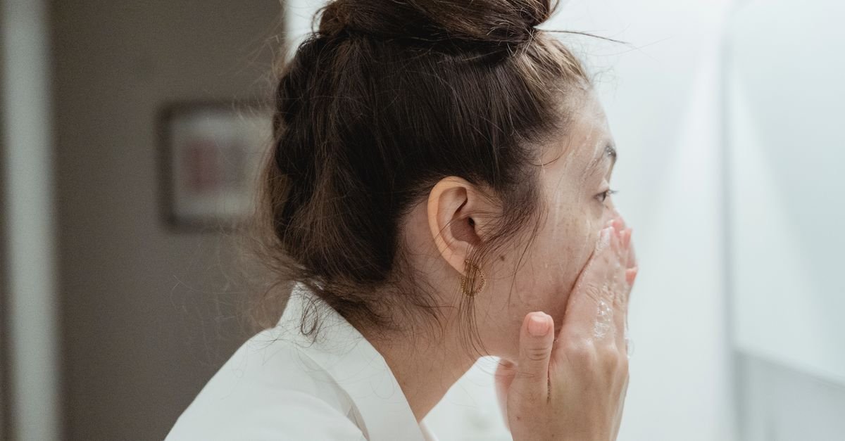 A teen washing her face at the bathroom sink