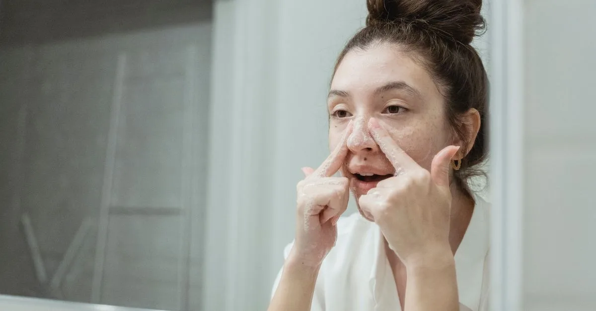 A teenager inspecting her nose in the mirror