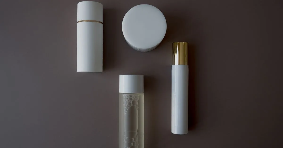 Minimal unbranded skincare containers on a dark background