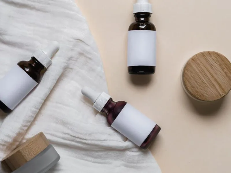Amber skincare bottles with wooden caps in a minimal flat lay