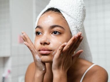 A teenage girl with a towel washing her face