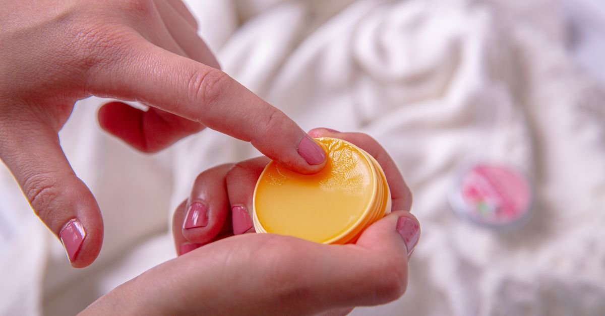 A finger dipping into a tin of lip balm