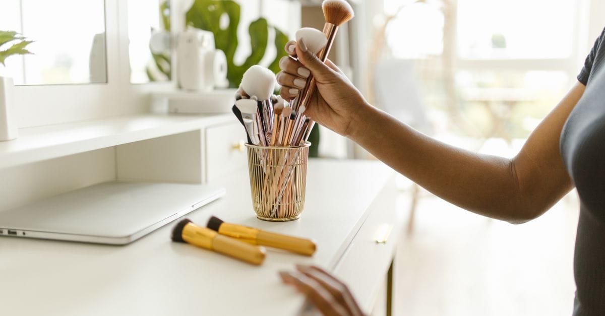 A hand reaching for brushes at a tidy vanity