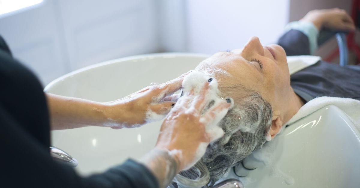 A scalp being shampooed and massaged at a salon basin