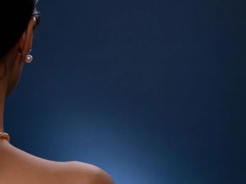 The back and shoulders of a woman against a dark background