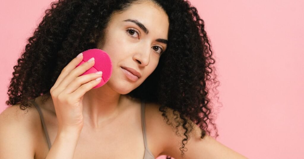 Woman holding a pink silicone cleansing device